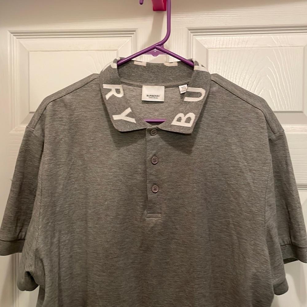 Mens Burberry polo in grey. White white Burberry across the collar.